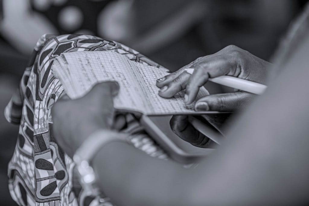 Monochrome close-up of hands writing in a notebook, emphasizing creativity and focus.