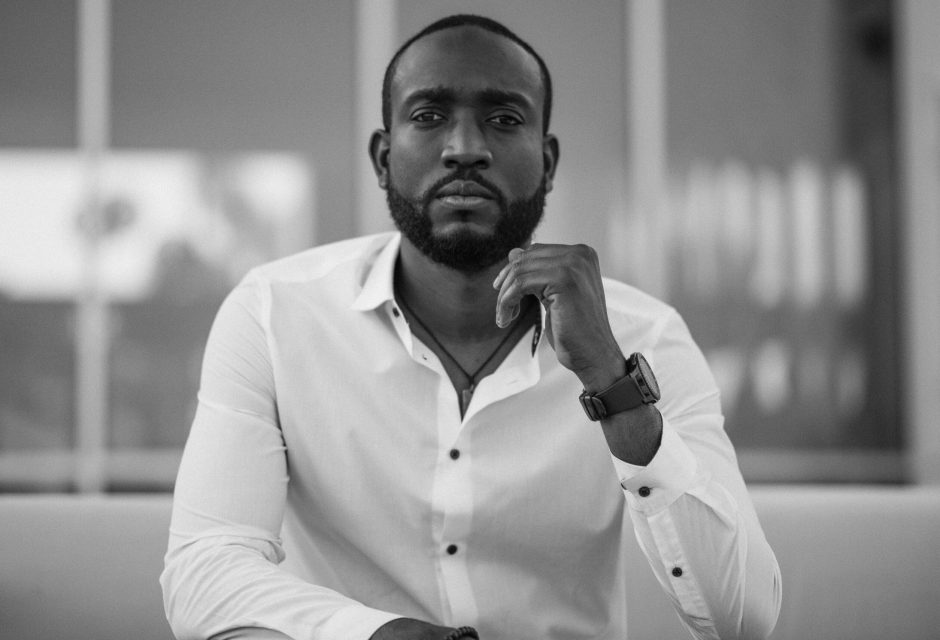 Black and white portrait of a stylish man in a white shirt indoors.